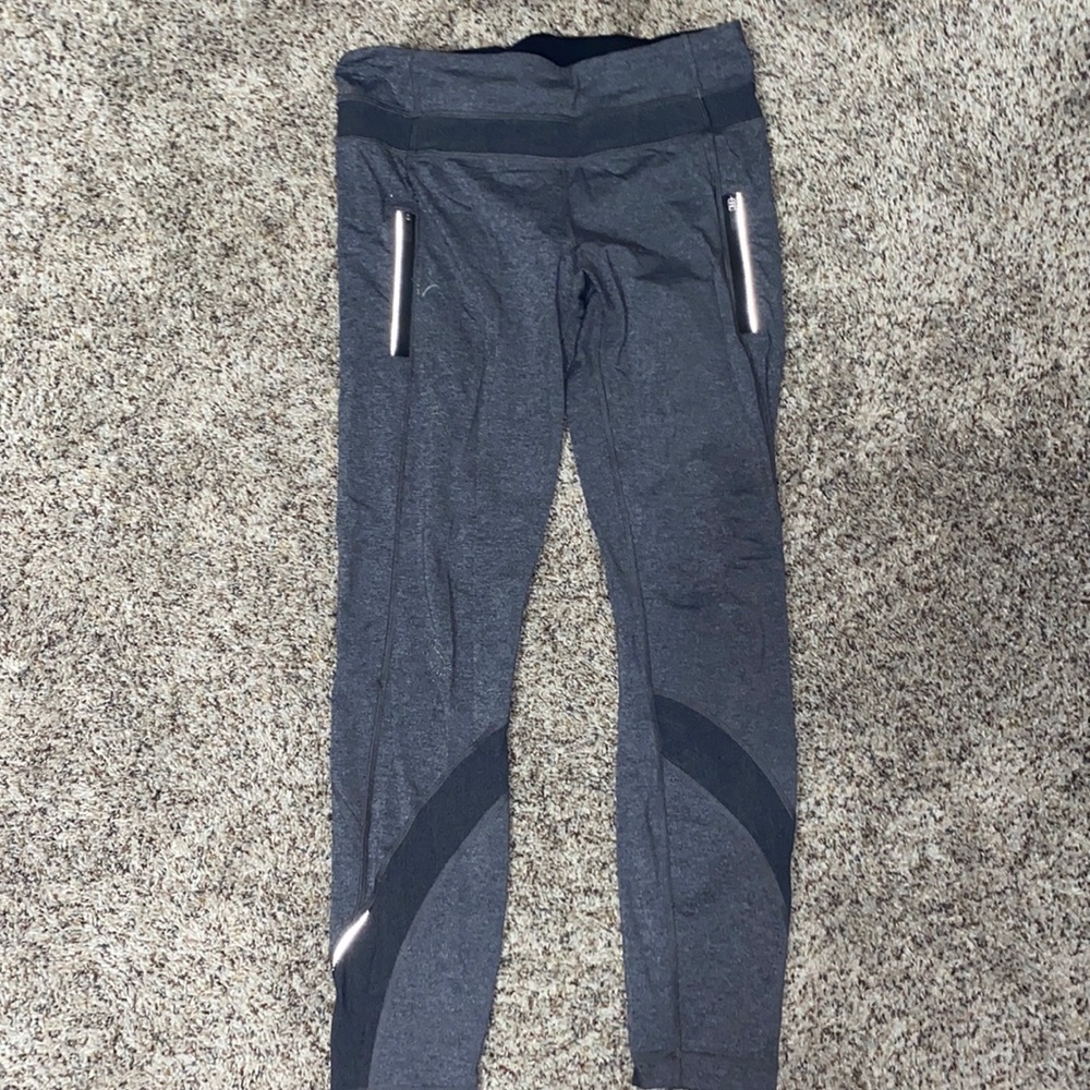 Grey lululemon leggings. pockets and reflective on the logo and the bottom.